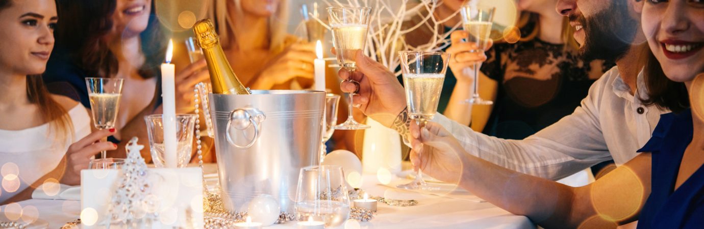 Friends celebrating Christmas or New Year eve. Party table with champagne.