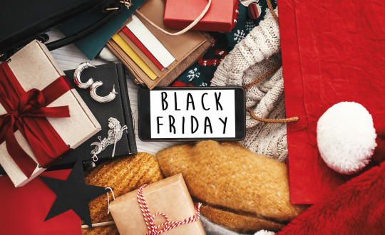 Black Friday big sale text on phone screen, flat lay. Special discount christmas offer. Phone with advertising message at money, wallet, bags, clothes, gift boxes, price tags. Shopping time