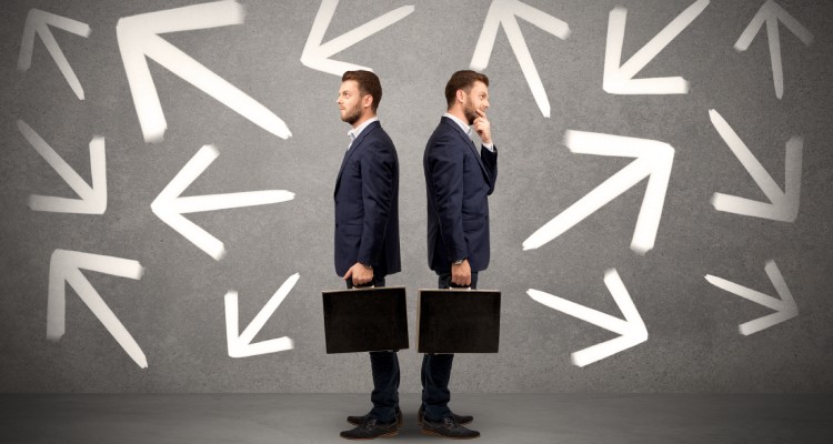 Young conflicted businessman choosing between two directions with arrows around him